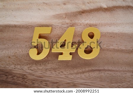 Gold numerals 548 on a dark brown to off-white wood pattern background.