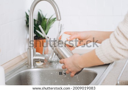 Woman washes a metal reusable bottle with an eco-brush. Zero waste Royalty-Free Stock Photo #2009019083