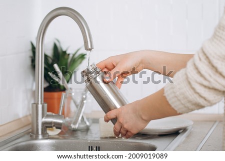 Woman washes a metal reusable bottle with an eco-brush. Zero waste Royalty-Free Stock Photo #2009019089