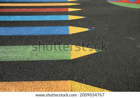 Color craons pencils zebra crossing painted on black road surface.
