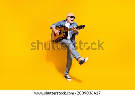 Full length photo of cool happy positive old man dance hold guitar wear sunglass isolated on yellow color background