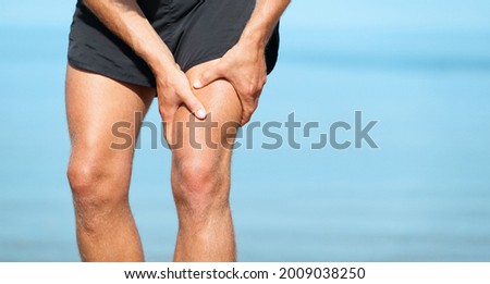 Sports injury muscle cramp pain fit runner man athlete holding painful thigh leg on outdoor summer jogging exercise. Fitness lifestyle. Royalty-Free Stock Photo #2009038250