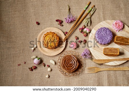 Mid Autumn festival food and drink on rustic background. Variety of mooncake and seeds. Text translation: Pure Lotus                 