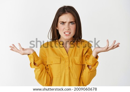Confused and nervous woman asking what, spread hands sideways and staring at camera puzzled, cant understand whats happening, standing over white background Royalty-Free Stock Photo #2009060678