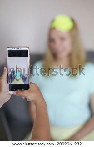 children's hands hold the phone and take pictures of the girl on the smartphone. Shallow depth of field.
