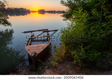 an abandoned boat at sunset by the river