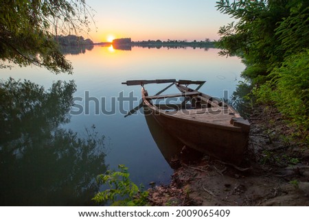 an abandoned boat at sunset by the river