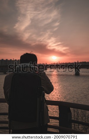 A photographer taking pictures of a beautiful sunset over the cityscape
