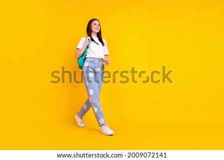 Full body profile side photo of young attractive girl happy positive smile go walk step backpack isolated over yellow color background
