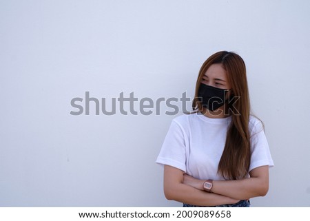 Portrait of a long-haired Asian woman Wear a mask to prevent germs. Stand with your arms crossed. Leave space for text on a white background.