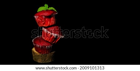 Closeup of delicious Red Velvet cupcakes or muffins decorated in tier with mint on top in a isolated black background with copy space and selective focus. Dessert. Bakery.