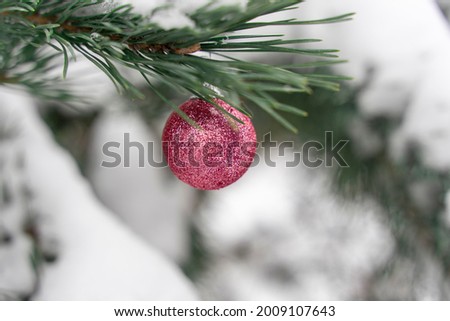 pink glittering Christmas ball on the branches of a fir-tree covered with snow. christmas background