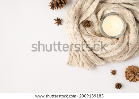 Top view photo of lighted candle in candlestick sweater pine cones and anise on isolated white background with blank space