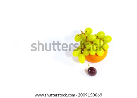 Fruits: orange tangerine, ripe burgundy cherry and green grapes on a white background isolated close-up