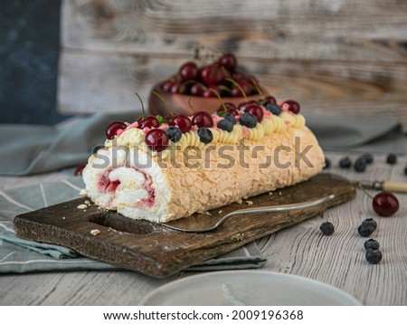 airy meringue cake with cherries on a brown board