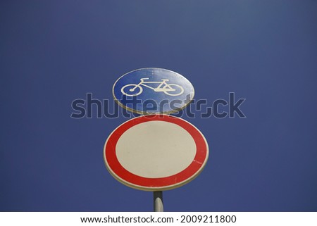 a banning road sign and a bicycle sign on blue background