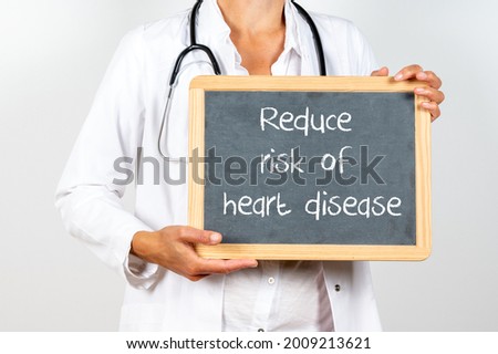 A blackboard with ''Reduce risk of heart disease'' written on it in the hands of a doctor