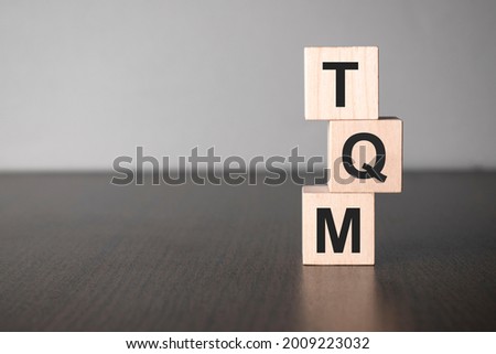 Businesswoman made word tqm with wood building blocks.