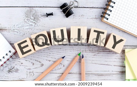 EQUITY text on wooden block with office tools on wooden background