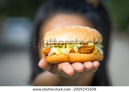 close up of tasty burger. woman hand holding juicy hamburger. concept hamburger at street food festival. summertime. summer vacation picnic. space for text