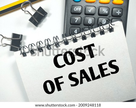Business concept.Text COST OF SALES on notebook with paper clips, calculator and pencil on white background.