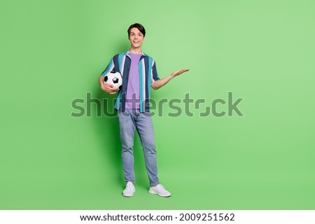 Full size photo of young happy cheerful man wear jeans hold hand empty space isolated on green color background