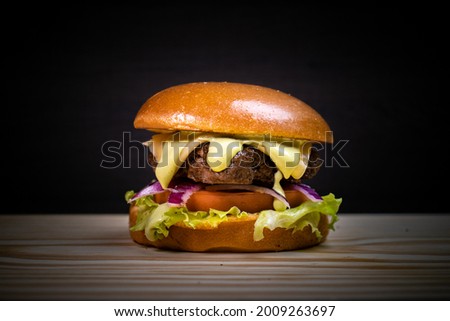 Tasty Classic Burger with Mayo and Soft Bun over Wooden Table and Dark Background