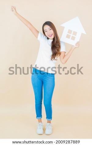 Portrait beautiful young asian woman show home sign paper on cream background