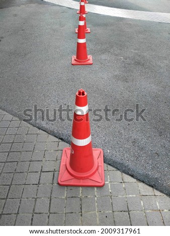 A traffic cone divides the lane of cars in the parking

