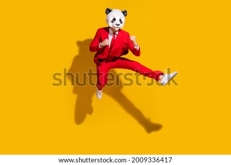 Photo of kung-fu panda guy jump hold fists kick leg empty space wear mask red tux shoes isolated on yellow color background