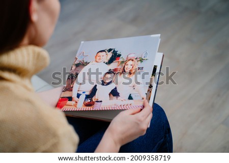 top view. a woman watches photobook from a family photo shoot. printed products. Store photos in an album. services of photographer and designer. memory of important moments of life.