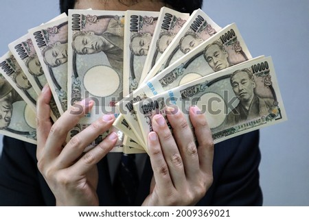 Japanese man with a large wad of bills.
translation:Common to all institutions,Manufactured by the National Printing Bureau,Yukichi Fukuzawa.