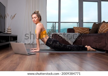 Woman doing online yoga at home. Female trener teaches asana in video conference. Health care, authenticity, sense of balance and calmness.