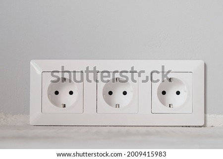 White electrical outlets with frame on gray wall background, close-up