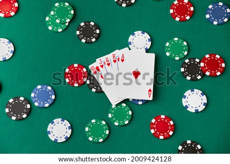 Casino pocker chips and playing cards on green fabric table