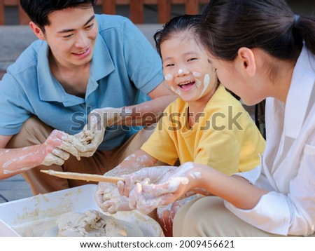 Happy family of three doing pottery together outdoors high quality photo