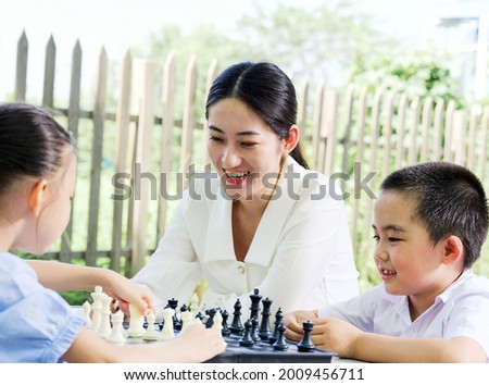 Happy family of three playing chess in the park high quality photo