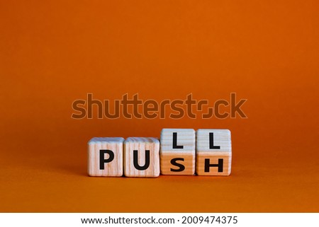 Pull or push symbol. Turned wooden cubes and changed the word 'push' to 'pull'. Beautiful orange background, copy space. Business and pull or push concept. Royalty-Free Stock Photo #2009474375