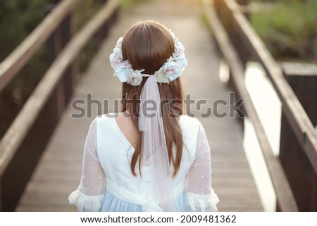 Young girl in white communion dress with a beautiful hairstyle. Royalty-Free Stock Photo #2009481362