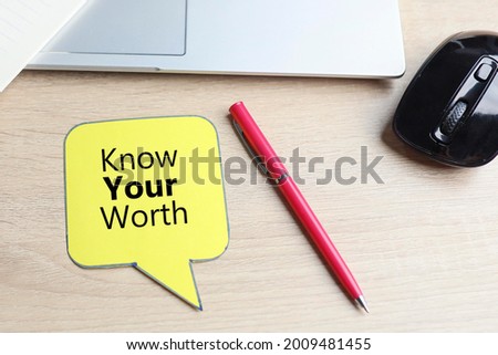 Know Your Worth message on the bubble speech, with pen, computer mouse and laptop on the wooden table 