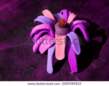 Lotus flower made with clay soft soil, presented on purple wood floor.