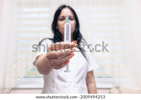 Nurse with a syringe in her hands. The nurse suggests an injection