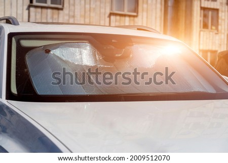 Sun visor or sun reflector on car windshield protects car in parking lot. There is light from sun shining on windshield Royalty-Free Stock Photo #2009512070
