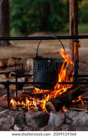A pot on the fire. Camping rest. Cooking in the forest. Vertical photo.