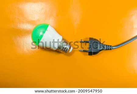 Abstract potrait of Green lamp and  electrical plug cable, isolated on orange background, July 14 2021.