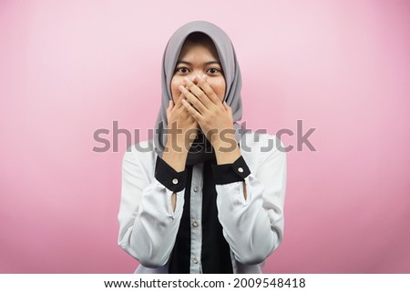 Beautiful young asian muslim woman shocked, surprised, disbelieving, getting shocking information, with hands covering mouth isolated on pink background