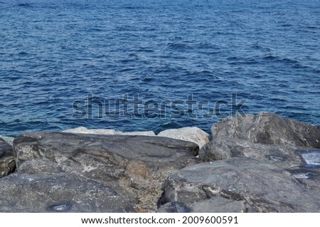 View of calm blue sea with grey rocks on the foreground. Copy space available. Royalty-Free Stock Photo #2009600591
