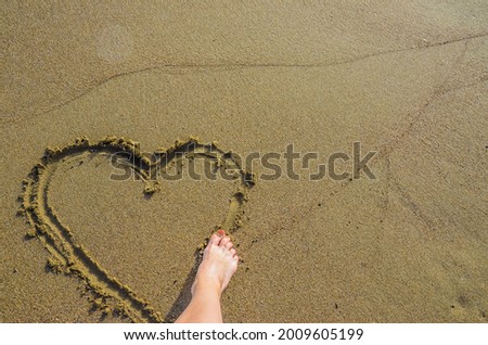 Heart drawn on the sand with a foot