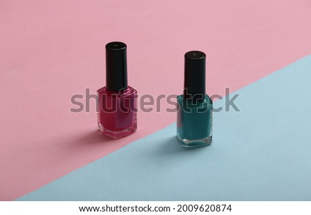 blue and pink nail polish bottles on a pastel background. Beauty still life