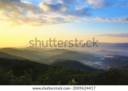 Beautiful dawn landscape with mountains and green trees under sunlight in summer

